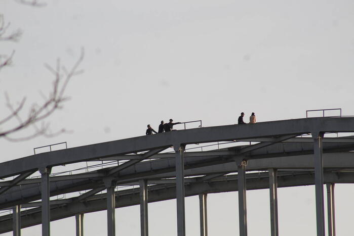 Persoon op bogen van brug, vele hulpdiensten aanwezig